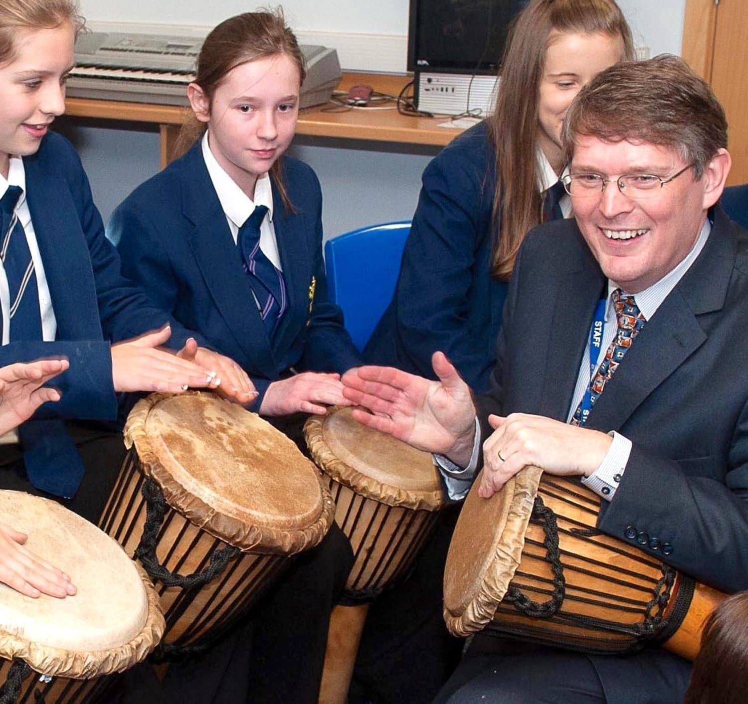 Secondary school students playing drums with teacher